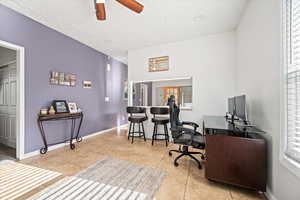 Office area featuring ceiling fan, light tile patterned floors, and a textured ceiling