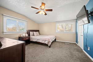 Carpeted bedroom with ceiling fan, lofted ceiling, and a textured ceiling