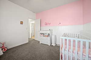 Carpeted bedroom with a textured ceiling and a nursery area