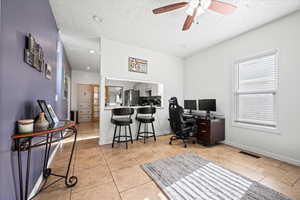 Tiled office space featuring ceiling fan and a textured ceiling