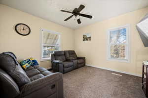 Carpeted living room with a textured ceiling and ceiling fan