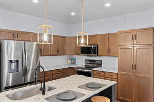 Kitchen with backsplash, pendant lighting, and appliances with stainless steel finishes