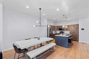 Kitchen featuring sink, stainless steel appliances, a kitchen breakfast bar, pendant lighting, and a center island with sink