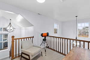 Living area with a notable chandelier, light carpet, and a wealth of natural light