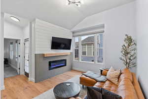 Living room with an inviting chandelier, lofted ceiling, and light hardwood / wood-style flooring