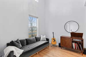 Sitting room with light hardwood / wood-style flooring and a towering ceiling