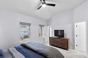 Bedroom with light carpet, vaulted ceiling, and ceiling fan