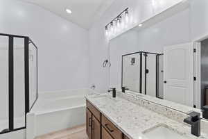 Bathroom featuring shower with separate bathtub, vanity, vaulted ceiling, and hardwood / wood-style floors