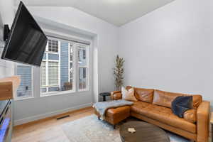 Living room featuring wood-type flooring and vaulted ceiling