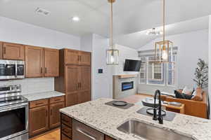 Kitchen with a notable chandelier, decorative light fixtures, appliances with stainless steel finishes, and tasteful backsplash