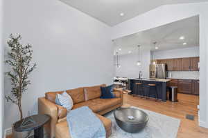 Living room featuring light hardwood / wood-style floors, lofted ceiling, and sink