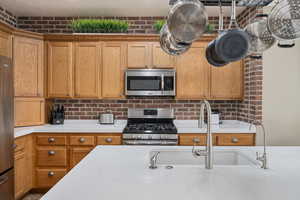 Kitchen featuring sink, stainless steel appliances, and brick wall