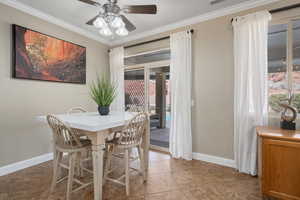 Tiled dining area with crown molding and ceiling fan