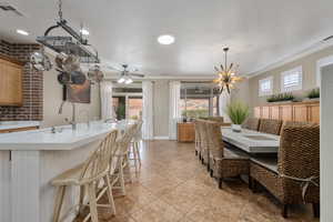 Dining space featuring a textured ceiling, ceiling fan, light tile patterned flooring, and crown molding