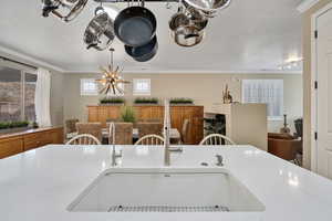 Kitchen featuring light stone countertops, sink, track lighting, a textured ceiling, and ornamental molding