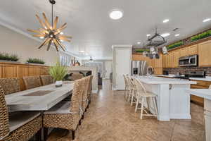 Dining room with ceiling fan with notable chandelier, crown molding, and sink