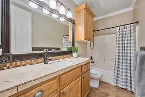 Full bathroom with tile patterned floors, crown molding, toilet, vanity, and shower / tub combo