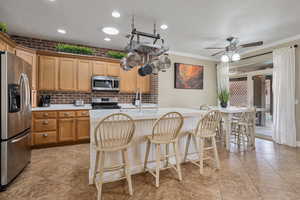 Kitchen featuring stainless steel appliances, ceiling fan, crown molding, and sink