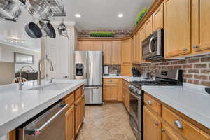 Kitchen featuring backsplash, stainless steel appliances, crown molding, sink, and light tile patterned floors