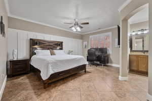 Bedroom with connected bathroom, ceiling fan, sink, a textured ceiling, and ornamental molding