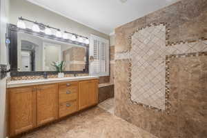 Bathroom featuring tiled shower, vanity, crown molding, and tile patterned flooring