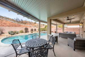 View of patio with a fenced in pool, a mountain view, ceiling fan, and an outdoor living space