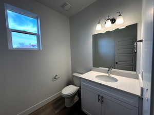 Bathroom with wood-type flooring, vanity, and toilet