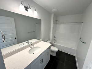 Full bathroom with vanity, tile patterned floors, shower / washtub combination, toilet, and a textured ceiling