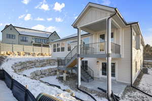 Snow covered back of property featuring cooling unit and a balcony