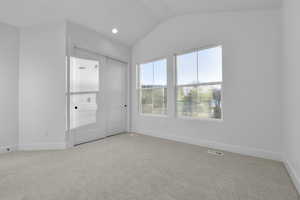 Unfurnished bedroom with lofted ceiling and light colored carpet