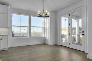 Unfurnished dining area with hardwood / wood-style floors and an inviting chandelier