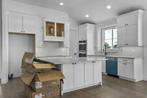 Kitchen featuring white cabinets, multiple ovens, dishwasher, and a kitchen island