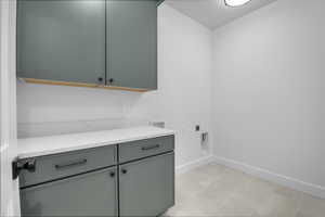 Clothes washing area featuring electric dryer hookup, hookup for a washing machine, and cabinets