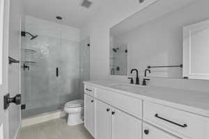 Bathroom featuring tile patterned flooring, vanity, a shower with door, and toilet