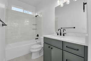 Full bathroom featuring tiled shower / bath combo, vanity, tile patterned floors, and toilet