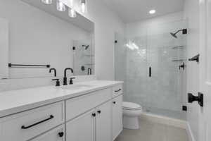 Bathroom with tile patterned floors, toilet, a shower with shower door, and vanity