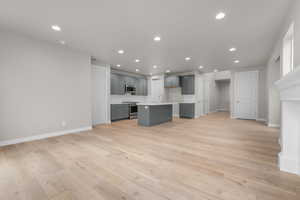 Kitchen featuring a center island with sink, gray cabinetry, light wood-type flooring, and stainless steel appliances