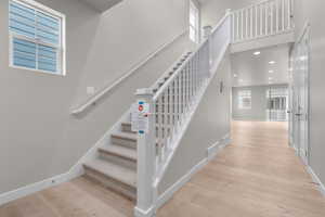 Stairs with hardwood / wood-style floors and a high ceiling