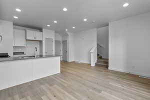 Kitchen featuring kitchen peninsula, sink, white cabinets, and light hardwood / wood-style floors