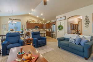 Living room with a notable chandelier, lofted ceiling, and light carpet