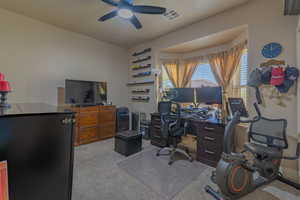 Carpeted office featuring ceiling fan