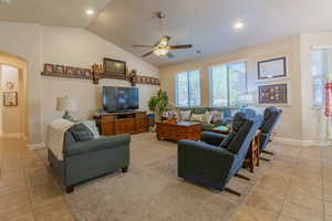 Tiled living room with ceiling fan and vaulted ceiling