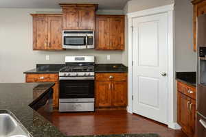 Kitchen with dark stone countertops, dark hardwood / wood-style floors, and appliances with stainless steel finishes