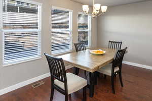 Dining area with dark hardwood / wood-style floors and a notable chandelier