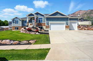 Craftsman-style home with board and batten siding, an attached garage, driveway, and stone siding
