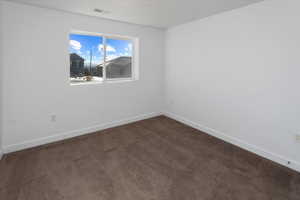 Empty room featuring dark colored carpet