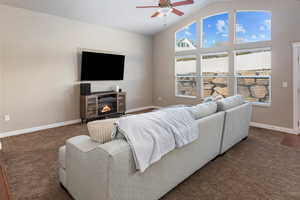 Carpeted living room featuring ceiling fan and vaulted ceiling