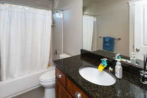 Full bathroom featuring vanity, shower / bath combination with curtain, and toilet