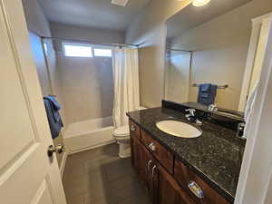 Full bathroom featuring vanity, shower / bath combination with curtain, and toilet