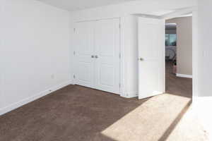 Unfurnished bedroom featuring dark carpet and a closet